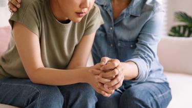 Mother holding hands with daughter, consoling the teen