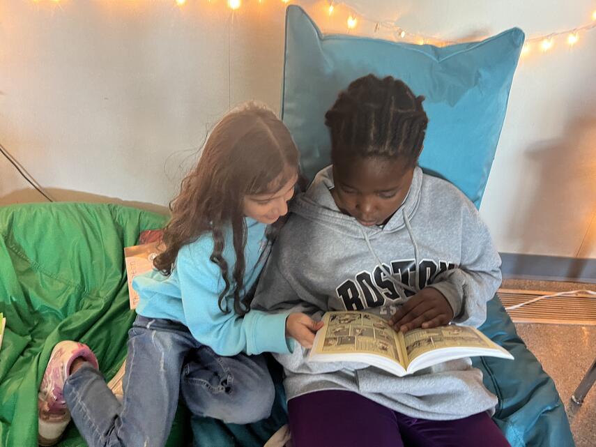 two students sharing a book together in a cozy nook