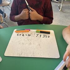 student adding numbers together with cuisenaire rods