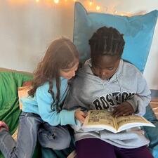 two students sharing a book together in a cozy nook